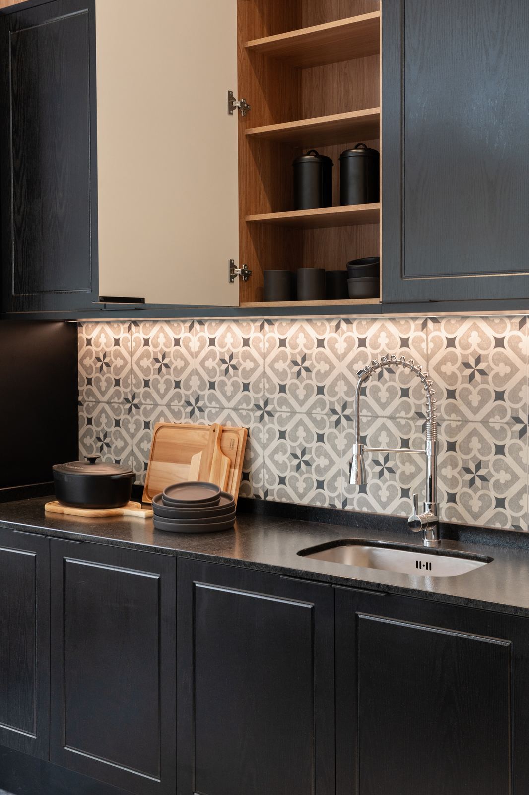 Detalhe de cozinha planejada preta com revestimento decorado e torneira gourmet, projeto Domus Italínea